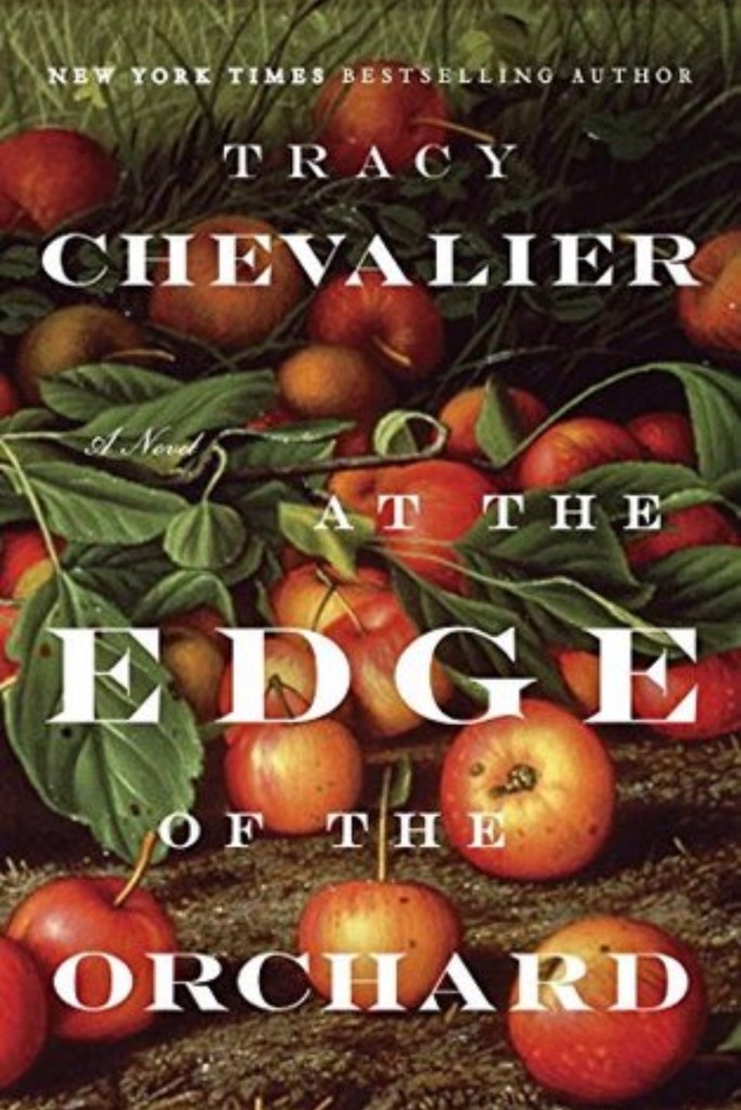 Book Cover of At the Edge of the Orchard by Tracy Chevalier, featuring colorful apples and foliage surrounding the tittle. 